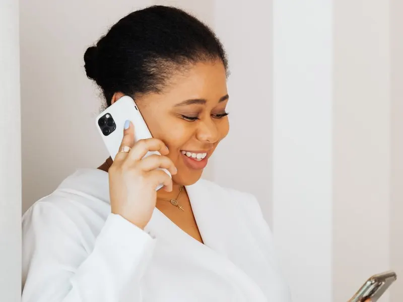 A smiling woman checking her smartphone while on a call